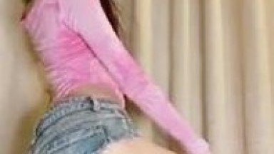 Chinese mature woman with long legs, wearing a pink outfit and jeans, dancing suggestively and masturbating.